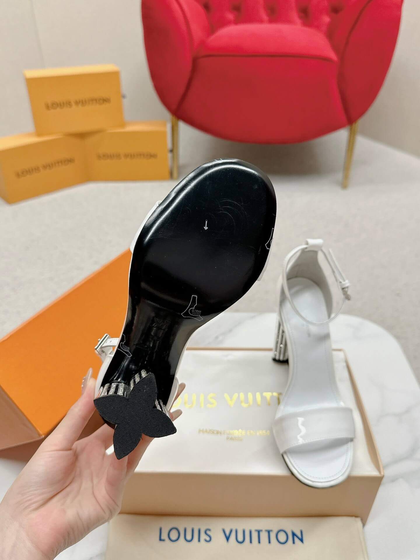 a pair of Louis Vuitton White Patent Leather Silhouette Sandals with Monogram Heel on a box