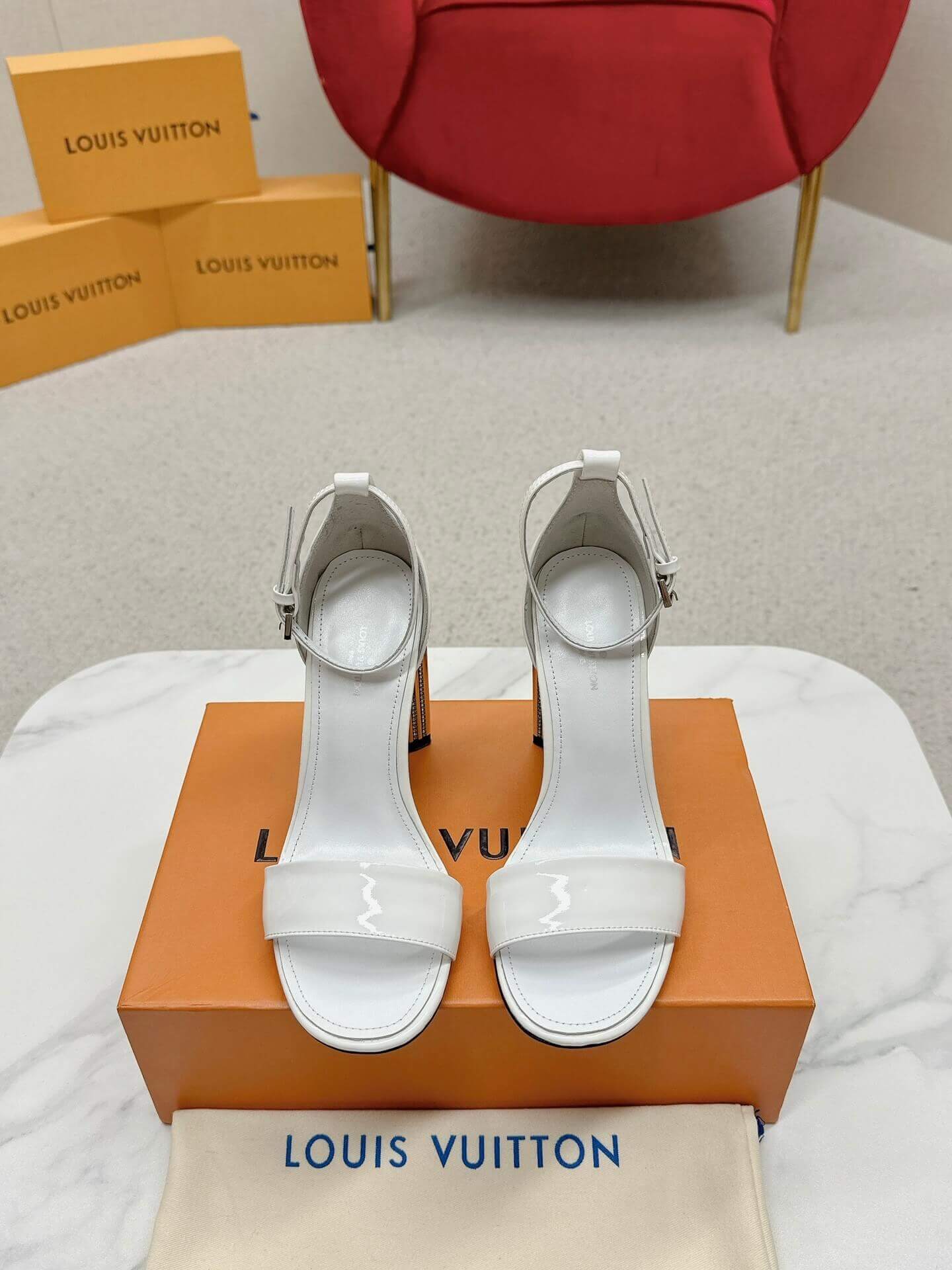 a pair of Louis Vuitton White Patent Leather Silhouette Sandals with Monogram Heel on a box