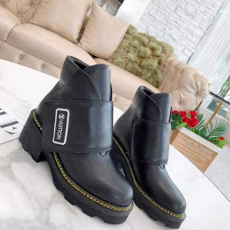 a pair of Louis Vuitton Wonderland Flat Ranger Boots in Black Leather on a marble table