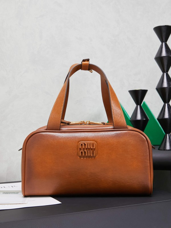 Miu Miu Tan Leather Top Handle Bag with embossed logo and gold-tone zip closure.