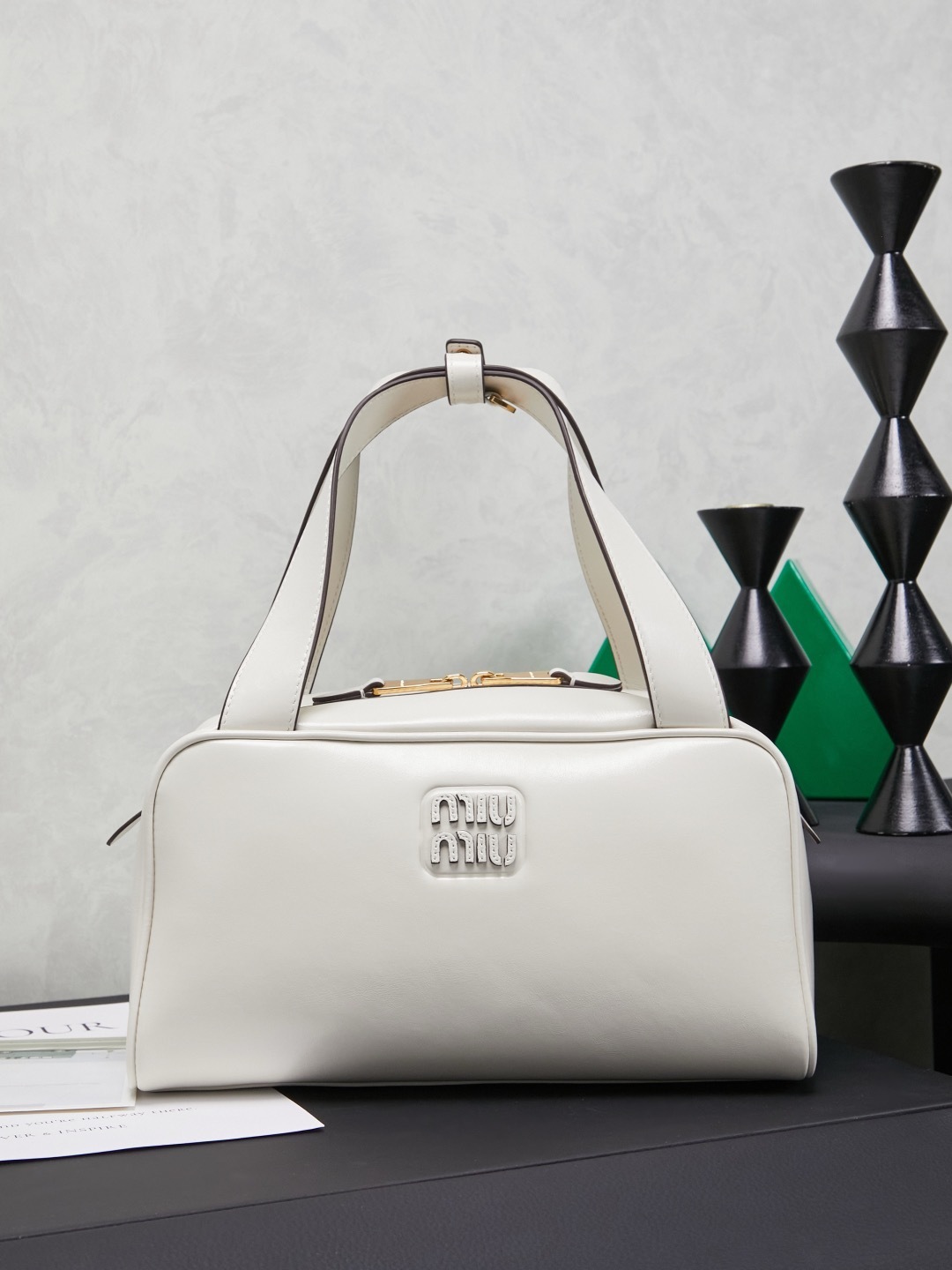 white Miu Miu leather Boston bag with embossed logo and dual top handles.