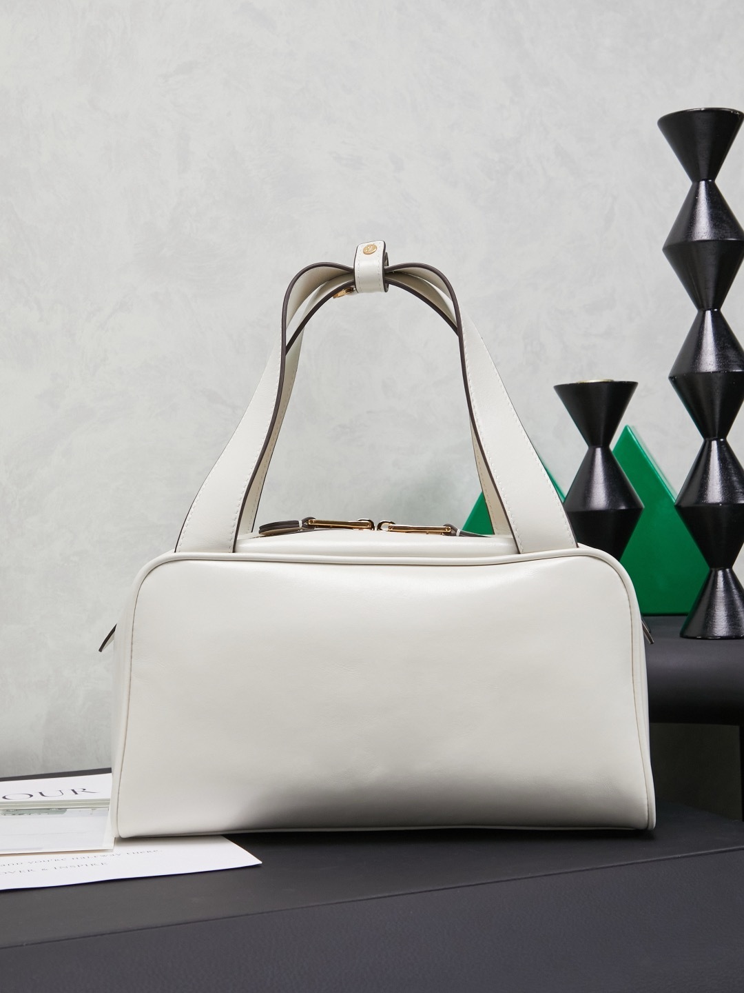 white Miu Miu leather Boston bag with embossed logo and dual top handles.