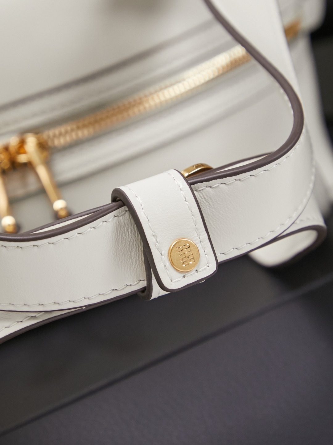 white Miu Miu leather Boston bag with embossed logo and dual top handles.