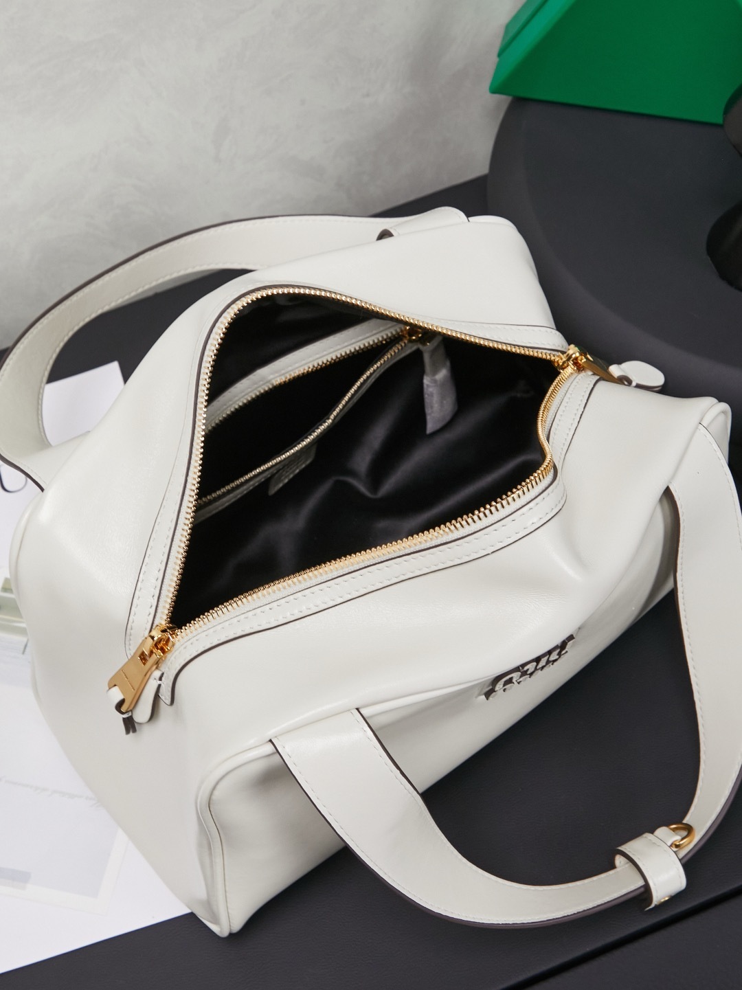 white Miu Miu leather Boston bag with embossed logo and dual top handles.