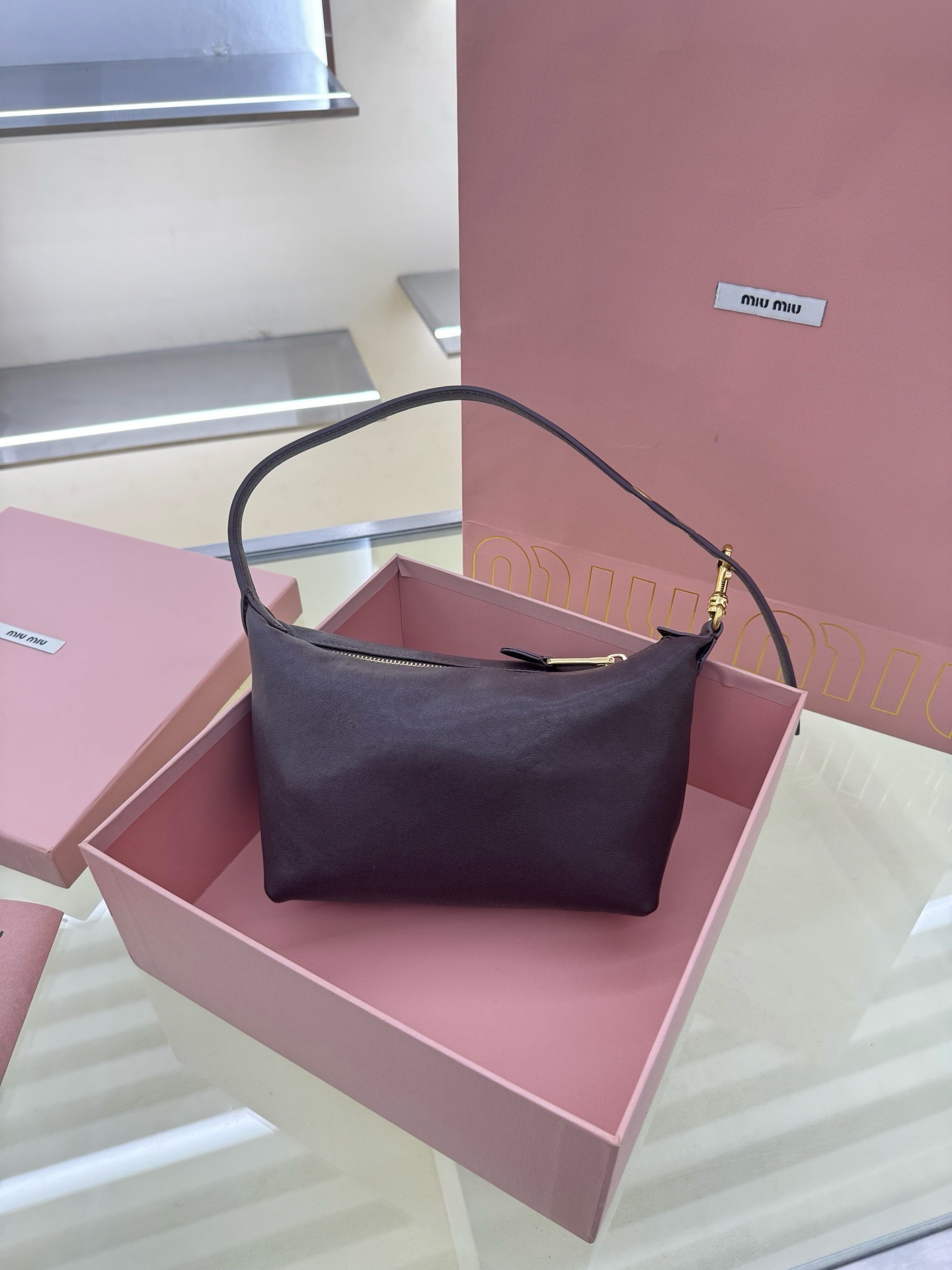 Miu Miu dark brown leather paddle shoulder bag front view in pink box