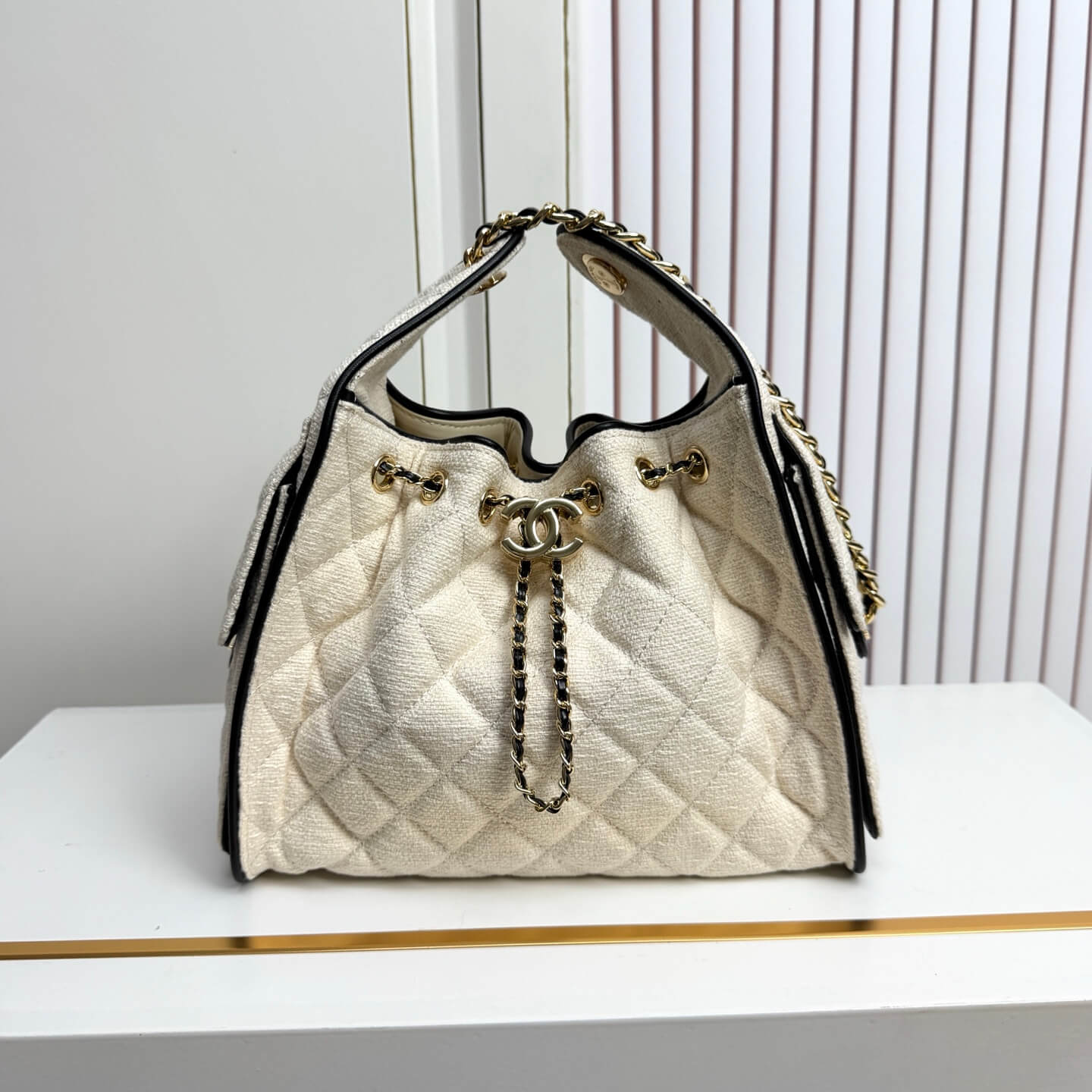 Chanel Quilted Canvas Hobo Bag with Black Trim and Gold-Tone Chain Hardware.